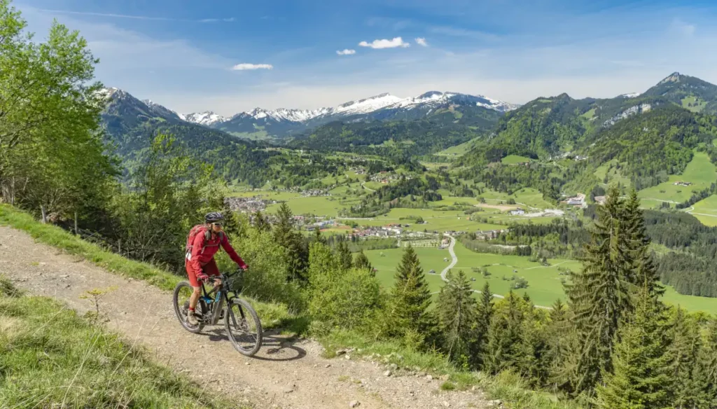 Seniorin auf elektrischem Mountainbike mit den Alpen im Hintergrund