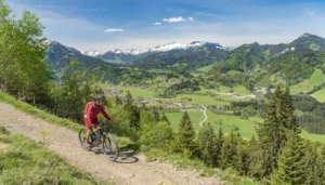 Seniorin auf elektrischem Mountainbike mit den Alpen im Hintergrund